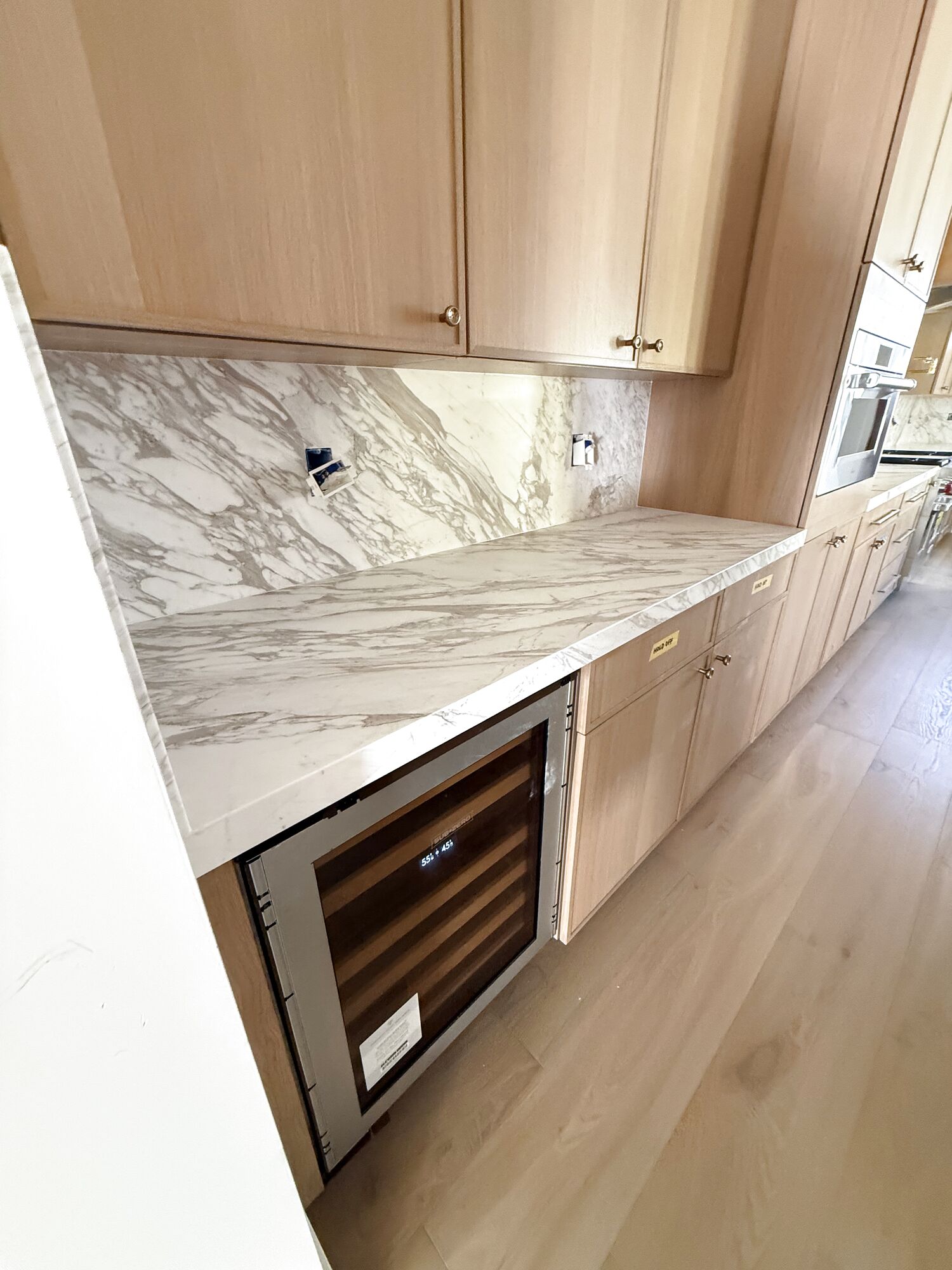 Marble counter and backsplash running over a built-in beverage center, set by Gallegos Custom Tile.